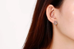 Close-up of silver hollow angel wing stud earrings worn on ear for elegant style
