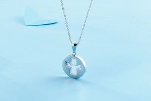 Close-up of silver stainless steel angel pendant necklace on a light blue background