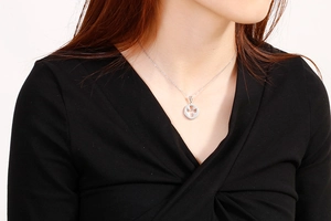 Detail of silver angel pendant necklace showing intricate hollow cross pattern on model