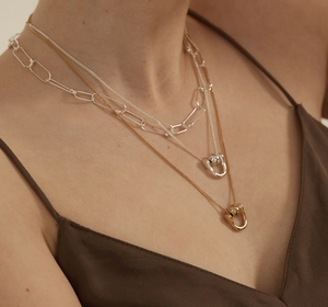 Detail of layered silver and gold horseshoe pendant necklaces worn by a model