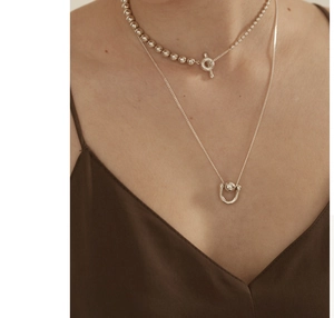 Detail of 925 sterling silver bead necklace with T-bar clasp on model's neck