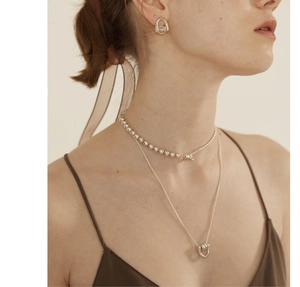 Detailed view of layered 925 sterling silver ball chains and earrings on a model