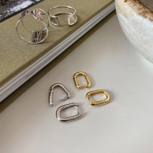 Macro detail of S925 sterling silver stamp on minimalist gold and silver oval hoop earrings