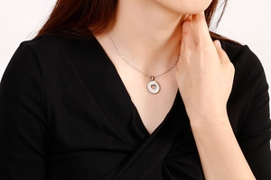 Detailed view of a silver heart cutout pendant necklace worn by a female model