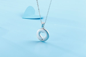 Detail view of silver heart pendant necklace with zircon on a light blue background