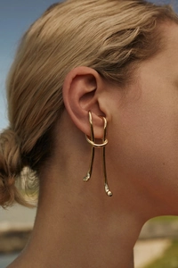 Detail of twisted gold knot earrings on model with polished metallic surface finish