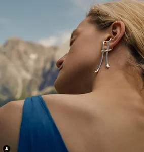 Minimalist silver S925 geometric knot ear cuff shown on model with outdoor background