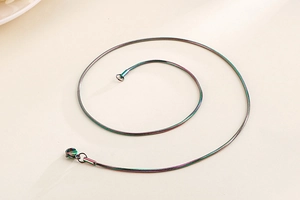 Macro shot of circular rainbow snake chain necklace with vibrant iridescent metallic finish