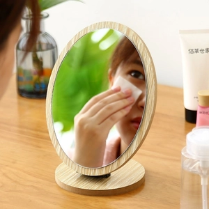 Minimalist oval desktop makeup mirror with a natural light wood frame and stable base