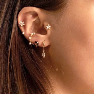 Golden earrings set with colorful zircon flowers and pearls on model's ear