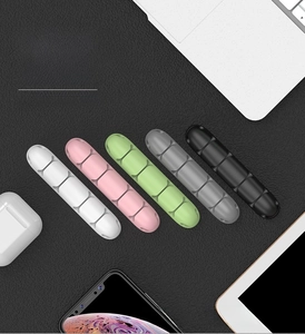 Five-slot silicone cable organizer in five colors on a professional office desk