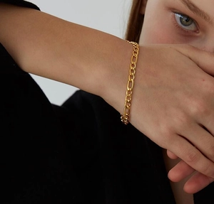 Primer plano de una pulsera de cadena Figaro de oro de 18K en la muñeca