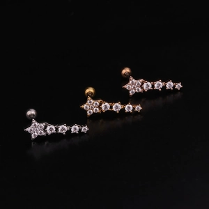 Detail of star-shaped zircon stud earrings in silver, gold, and rose gold finishes