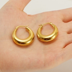Polished 18K gold plated hollow hoop earrings in stainless steel on a palm