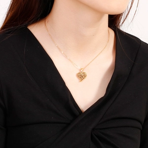 Parure collier et boucles d'oreilles cœur en acier titane doré portée par un mannequin