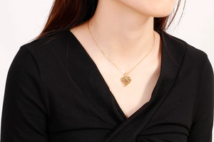Détail d'un collier pendentif cœur évidé porté au cou avec une finition texturée spirale