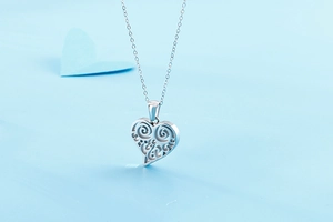 Gros plan d'un collier pendentif cœur argenté sur un fond bleu clair romantique