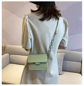 Close-up of mint green square crossbody bag with matching resin chain strap on a model
