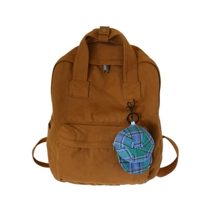 Brown canvas backpack for women with a blue checkered hat keychain accessory on white background