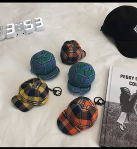 Detail view of five checkered flat cap keychains in various colors with metal rings
