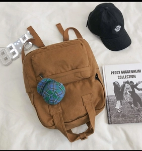 Flat lay detail of brown canvas backpack with adjustable straps and casual styling