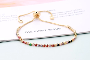 Macro detail of adjustable gold bracelet featuring vibrant multi-colored cubic zirconia stones
