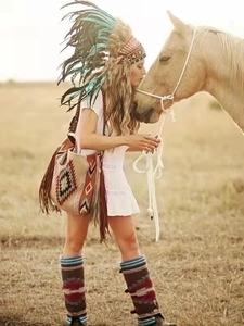 Detailed view of bohemian fringe shoulder bag and woven boots in an outdoor setting