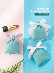 Three Tiffany blue velvet jewelry pouches with silk ribbons on a marble tray
