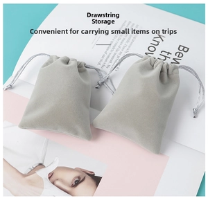 Macro detail of two light grey velvet drawstring pouches with elegant silver ribbon cords