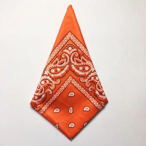 Detail of orange paisley bandana folded in triangle shape with white floral pattern