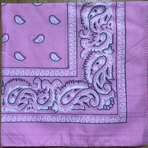Flat lay of a pink paisley bandana with traditional cashew flower pattern on wood surface