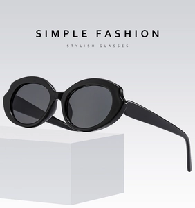 Macro shot of black oval frame sunglasses with shiny finish and silver metal hinges