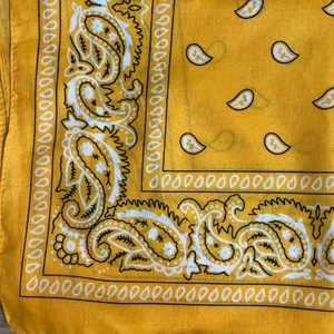Detailed close-up showing the yellow paisley pattern and woven texture of the bandana