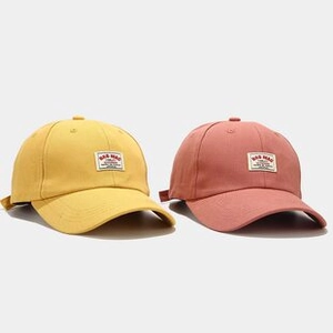 Detailed close-up of macaron yellow and red cotton sun hats with 'BAD MAN' logo patches