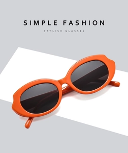 Detail view of bright orange retro oval sunglasses with dark lenses on geometric background