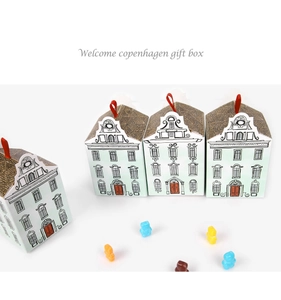 Detail of house-shaped gift boxes with red ribbons and colorful gummy bear accents