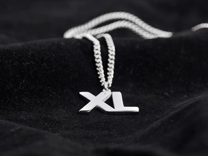 Macro shot of polished silver stainless steel XL alphabet pendant on Cuban chain necklace