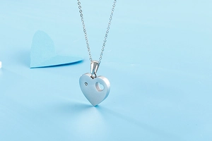 Detailed view of silver heart pendant with brushed finish and small inlaid diamond