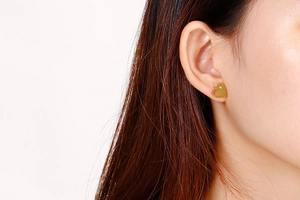 Close-up of heart-shaped gold stud earring with diamond on model's ear