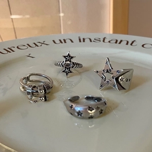 Dettaglio di anelli a stella in argento retrò su piatto bianco con marchio 925 e testo