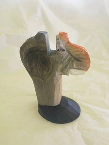 Detailed close-up of a hand-carved wooden elephant spectacle holder on a black base
