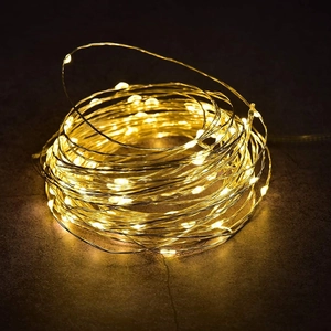 Close-up of warm white LED copper wire string lights coiled on dark stone surface