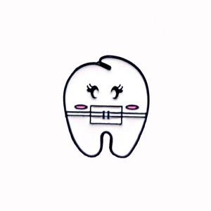 Detail of cute tooth-shaped cartoon brooch with white enamel finish and pink blush accents