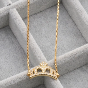 Detail of a gold crown pendant with cubic zirconia stones displayed in a grey velvet box