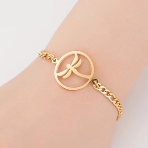 Detail of a gold titanium steel bracelet with a hollow dragonfly charm worn on the wrist
