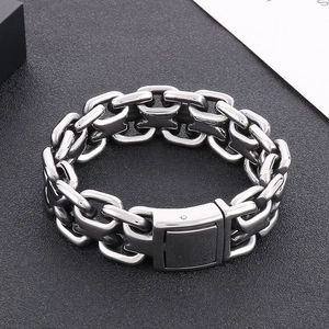 Close-up of a men's chunky polished stainless steel Cuban link bracelet on a dark surface