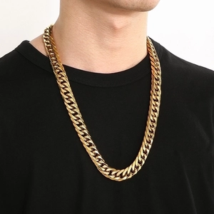 Close-up of a men's heavy gold cuban link curb chain worn by a male model on a black tee