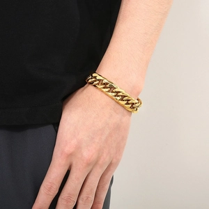 Detail of a bold gold Cuban link bracelet for men styled on a male model's wrist