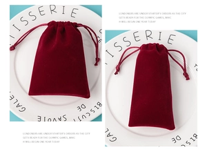 Detail of burgundy velvet drawstring gift pouches placed on a white decorative plate