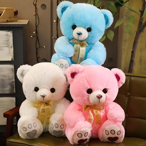 Three plush teddy bears in blue, white, and pink with ribbon bows and heart-shaped foot details